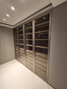 Modern built-in wardrobe with glass doors and ample shelving.
