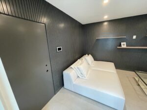Modern minimalist living room with dark walls and a white sofa.