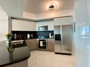 Modern kitchen with sleek black and white design and stainless steel appliances.