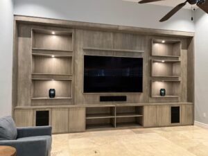 Modern wooden entertainment center with built-in lighting and a mounted TV.